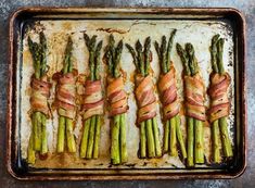 asparagus wrapped in bacon on a baking sheet