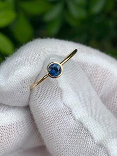 a gold ring with a blue stone on it sitting on top of a white cloth