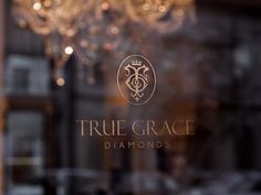 the logo for true grace diamonds in front of a chandelier and glass window