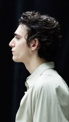 a young man with curly hair is looking off to the side