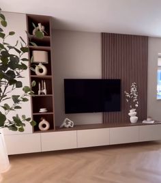 a living room with a large television on top of a wooden entertainment center next to a potted plant