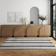 a living room with white walls and wooden flooring next to a large mirror on the wall