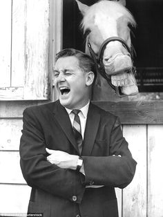 a black and white photo of a man with his mouth open next to a horse