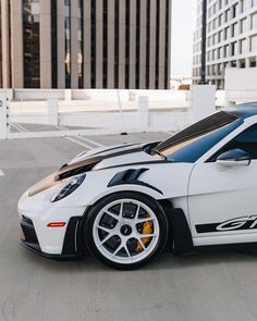 a white sports car parked in front of a tall building