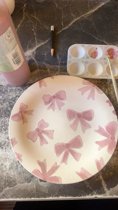 a plate with pink bows on it next to some paint