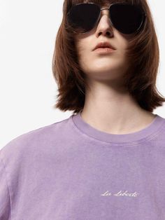 a woman wearing sunglasses and a purple shirt