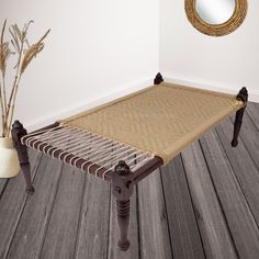 a bed frame sitting on top of a wooden floor next to a vase with flowers