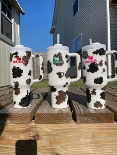 three coffee mugs with black and white designs on them are sitting on wooden boards