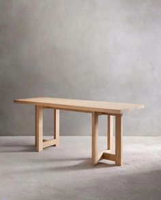 a wooden table sitting on top of a white carpeted floor next to a gray wall