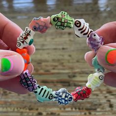 two hands holding colorful bracelets with different designs on them and one hand is holding the other