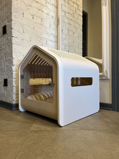 a white microwave oven sitting on top of a floor next to a brick wall and mirror