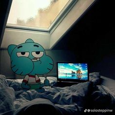 a laptop computer sitting on top of a bed next to a cartoon character wallpaper