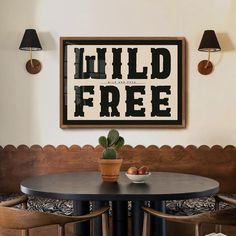 a table with two chairs and a potted plant on it in front of a framed poster