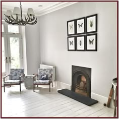 a living room filled with furniture and a fire place under a chandelier on top of a hard wood floor