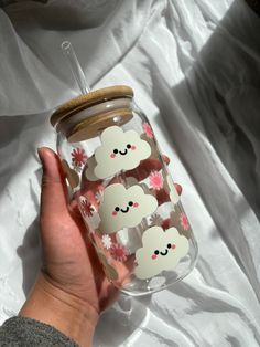 a hand holding a glass jar with stickers on it