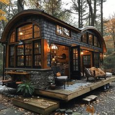 a small cabin in the woods with lots of windows on it's roof and deck