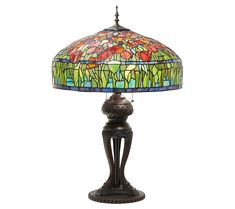 a stained glass lamp on a table with a metal base and flower design in the center