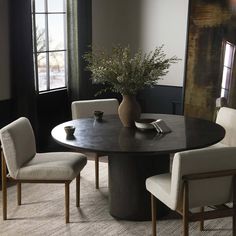 a round table with four chairs around it and a vase filled with flowers on top