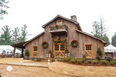 a large wooden building with wreaths on the front and windows, surrounded by greenery