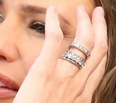 a close up of a person with rings on their fingers and her hand near her face