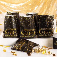 black and gold party bags with confetti in them on a white table surrounded by streamers