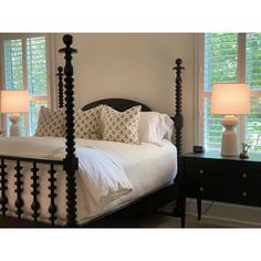 a bed with white sheets and pillows in a bedroom next to two lamps on either side of the bed