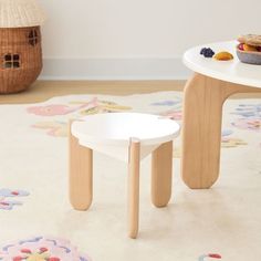 a white table with two small stools on top of it in front of a rug