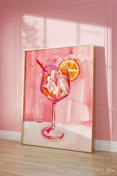 a pink painting with an orange slice and a wine glass on the table in front of it