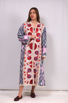 Cotton ikat kaftan, adorned with vibrant Suzani embroidery featuring striking red pomegranates and flowers on the front. This  masterpiece marries the comfort of cotton with the artistry of handcrafted Suzani motifs, creating a uniquely stylish and comfortable wardrobe essential. This kaftan promises to be your go-to statement piece. Festive Ikat Print Kaftan, Traditional Pink Floral Print Kaftan, Traditional Pink Kaftan With Floral Print, Red Bohemian Kaftan With Resham Embroidery, Festive Multicolor Embroidered Kaftan With Embroidered Border, Festive Embroidered Kaftan With Border Detail, Traditional Floral Print Kaftan For Festivals, Multicolor Ikat Print Long Sleeve Kaftan, Multicolor Long Sleeve Ikat Print Kaftan