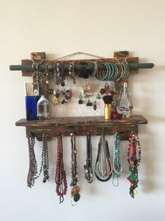 a wooden shelf with several necklaces hanging from it's sides and on the wall