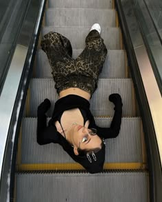 a woman is laying down on an escalator