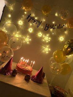 a birthday cake with lit candles and balloons