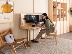 a woman sitting at a desk in front of a computer monitor on top of a wooden table