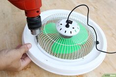 a person is using a drill to fix a fan