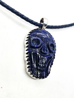 Lapis Lazuli hand carved skull pendant sterling silver custom corded chain. Good vintage condition with little signs of normal wear. Custom braided corded chain with sterling silver capped clasp. Clasp opens with push button on the side. Pendant is set in sterling silver with large saw tooth bezel. Pendant stamped on the back 925. Acid tests positive for sterling silver. Necklace measures 18 inches long. Pendant measures 2 inches long and 1 inch wide. Adjustable Carved Sterling Silver Jewelry, Carved Skull, Silver Caps, Saw Tooth, Skull Carving, Skull Pendant, Bezel Pendant, Long Pendant, Push Button