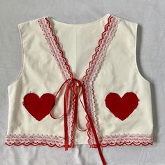 a white vest with red hearts on it and a ribbon tied around the waistline