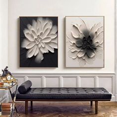 two black and white paintings on the wall above a bench in front of a fireplace