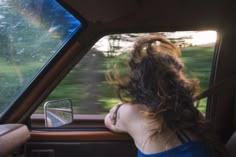 a woman sitting in the passenger seat of a car looking at her rear view mirror