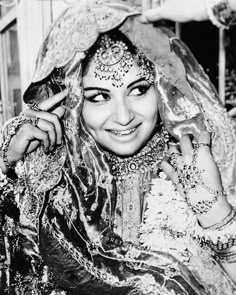 a woman in a veil and headdress poses for the camera with her hands on her face