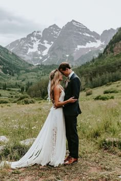 a bride and groom standing in the mountains