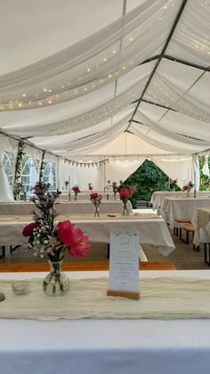 the tables are set up with white linens and flowers in vases on them