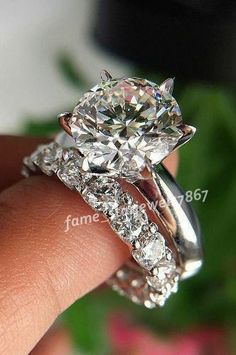 a close up of a person's hand holding a diamond ring