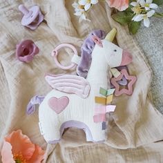 a stuffed unicorn sitting on top of a bed next to flowers