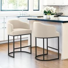 two white chairs sitting in front of a kitchen island