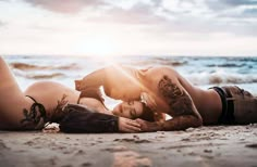 two women laying on the beach with their backs to each other and one is kissing