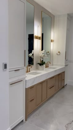 a bathroom with double sinks and large mirrors on the wall next to it's cabinets