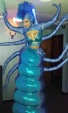 a woman in a blue costume standing on top of a plastic ball with her arms outstretched