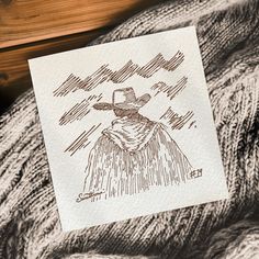 a piece of paper with a drawing of a man wearing a hat on top of a blanket