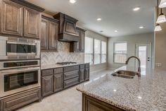 an empty kitchen with granite counter tops and stainless steel appliances in the middle of it