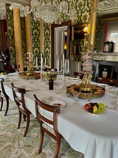 a dining room table is set up with plates and bowls of fruit on the table